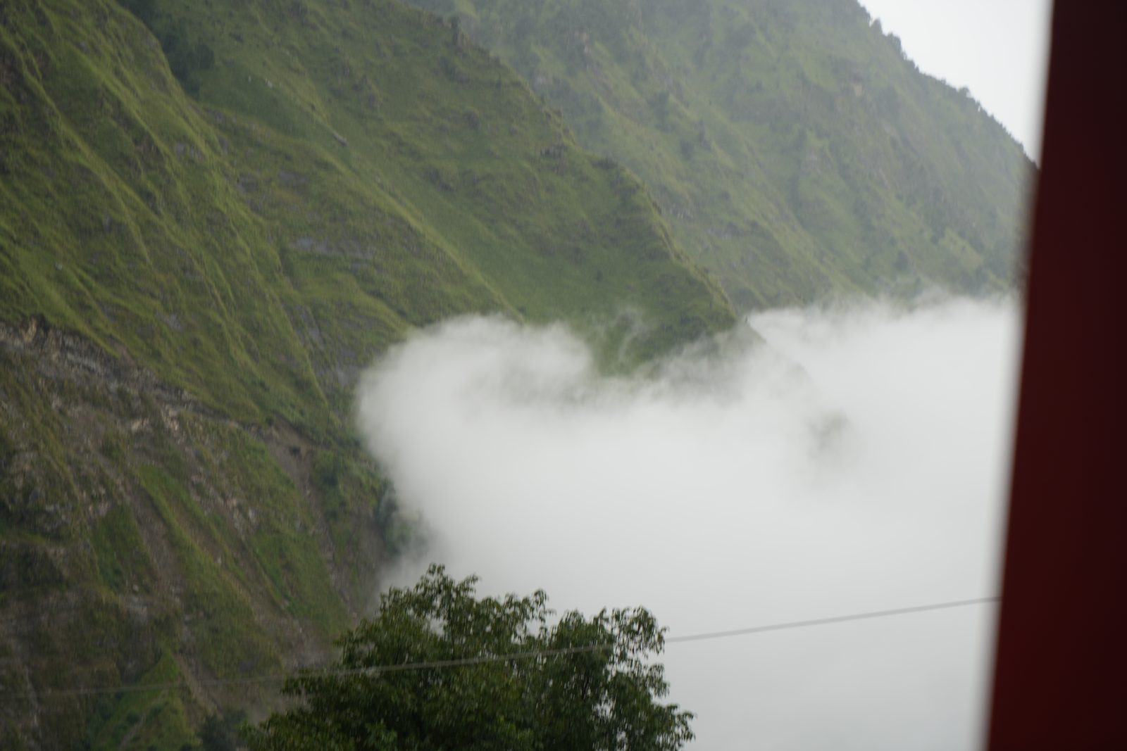 Cloud lifting off a steep green ridge and spilling across the slope below it.